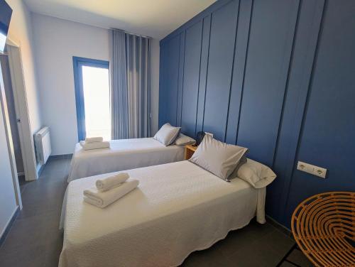 two beds in a room with blue walls at Hostal Náutico de Razo in Carballo