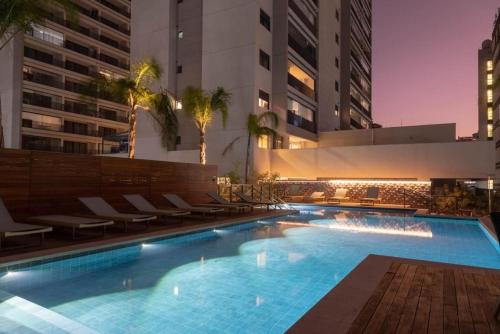 uma piscina com cadeiras e um edifício em Apartamento na paulista (com garagem) em São Paulo