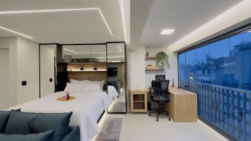 a bedroom with a bed and a desk and a balcony at Apartamento na paulista (com garagem) in Sao Paulo