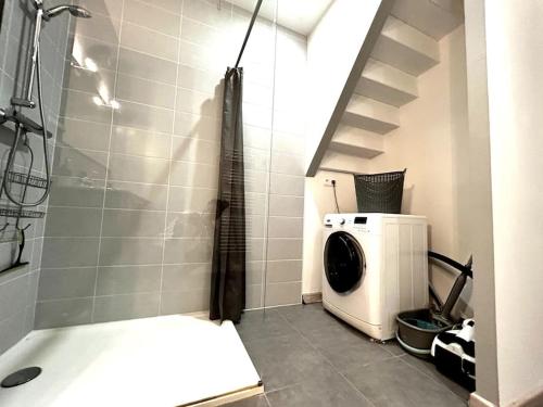 a bathroom with a washing machine and a shower at Logements situés en plein cœur de ville avec jardin in Rochefort