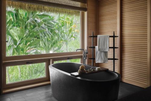 eine Badewanne in einem Zimmer mit einem großen Fenster in der Unterkunft Kona Village A Rosewood Resort in Kailua-Kona