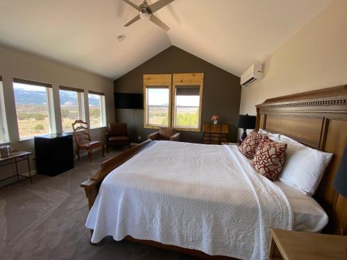 a bedroom with a large white bed and windows at SkyRidge Inn in Torrey