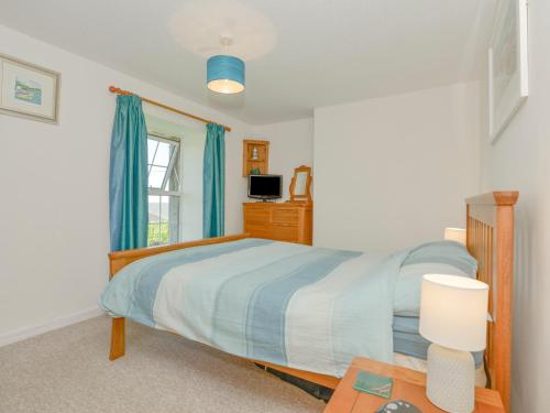 a bedroom with a bed and a window and a table at Primrose Cottage in Wadebridge