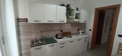 Una cocina con gabinetes blancos y un fregadero. en M7 Suites Central, en Salerno