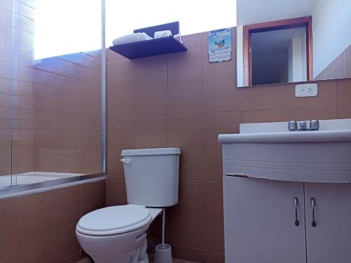 a bathroom with a toilet and a sink and a mirror at Hotel Versailles in Ambato