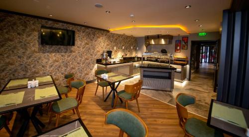 バンドゥルマにあるCITY ASYA HOTELのテーブルと椅子とキッチンのあるレストラン