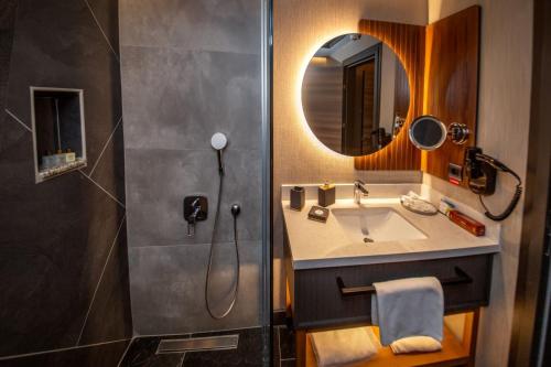 uma casa de banho com um lavatório e um chuveiro com um espelho. em CITY ASYA HOTEL em Bandirma