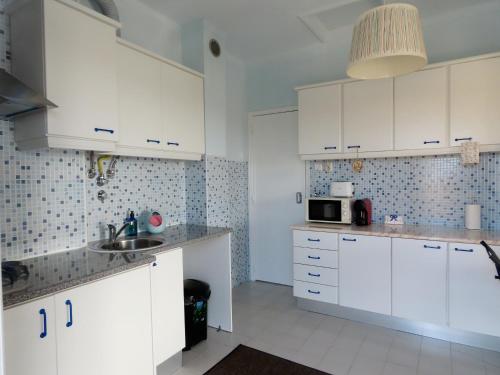 - une cuisine avec des placards blancs et un évier dans l'établissement Casa do Portão Azul - Espadarte, à Atouguia da Baleia