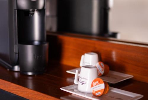 a table with two cups and a coffee maker at Pousada Suiça Mineira Centro in Monte Verde