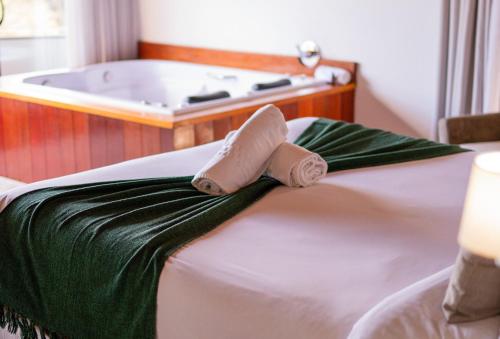 a bed with a towel on it with a bath tub at Pousada Suiça Mineira Centro in Monte Verde