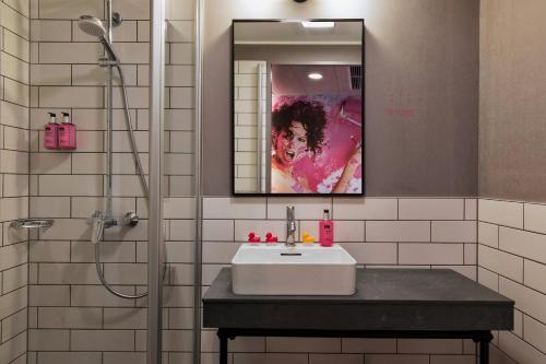 uma casa de banho com um lavatório, um espelho e um chuveiro em MOXY Frankfurt East em Frankfurt