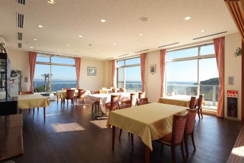 a restaurant with tables and chairs and large windows at Manazuru Marin Hotel in Manazuru