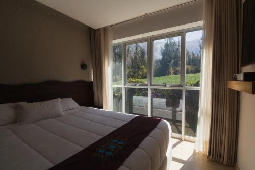 a bedroom with a bed and a large window at Hacienda del Valle Sagrado in Urubamba