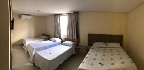 a hospital room with three beds and a window at Pousada Dubai in Itabuna
