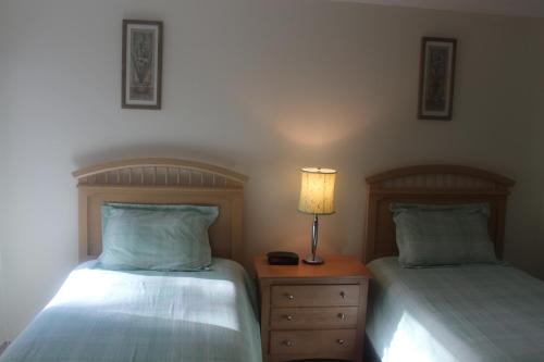 a bedroom with two beds and a table with a lamp at Exceptional New Seabury Mews Property in Mashpee