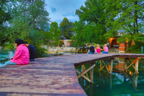 a group of people sitting on a bridge over water at Holiday Homes Pozitiva in Bihać