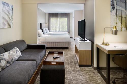 SpringHill Suites Charlotte University Research Park في تشارلوت: غرفة في الفندق مع أريكة وسرير