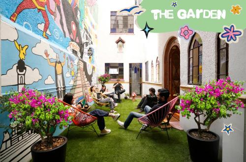 a group of people sitting in chairs in a building with flowers at Hostal Fungi Casa Rosa in Mexico City
