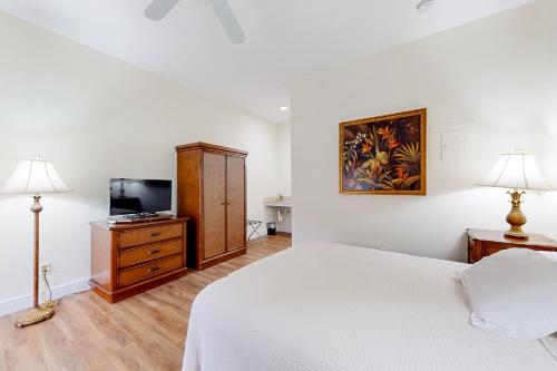 a white bedroom with a bed and a tv at Port of the Islands B111 in Naples
