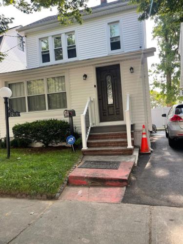 a white house with a door and a car parked in front at Home away from home in Laurelton