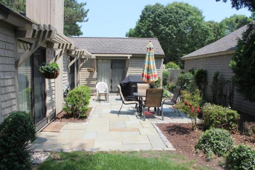 a patio with a table and chairs and an umbrella at Exceptional New Seabury Mews Property in Mashpee