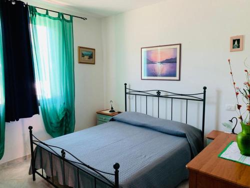 Schlafzimmer mit einem Bett, einem Tisch und Vorhängen in der Unterkunft Valledoria Residenza sole e mare in Codaruina