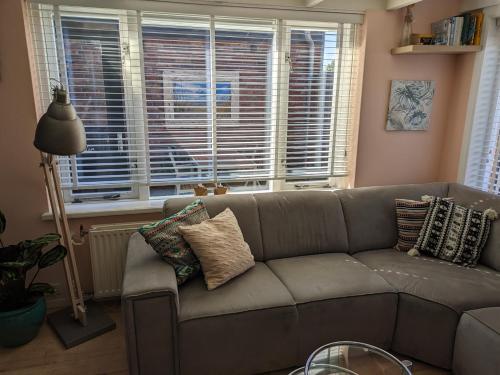 a living room with a couch and a window at Knus huisje met prachtige nieuwe badkamer - Distelhoek in Egmond aan Zee