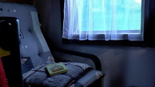a book sitting on a chair in a room with a window at Apartmani Planinska kuća, Jagodnja in Krupanj