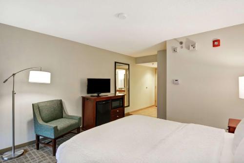 a hotel room with a bed and a chair and a television at Hampton Inn Beckley in Beckley