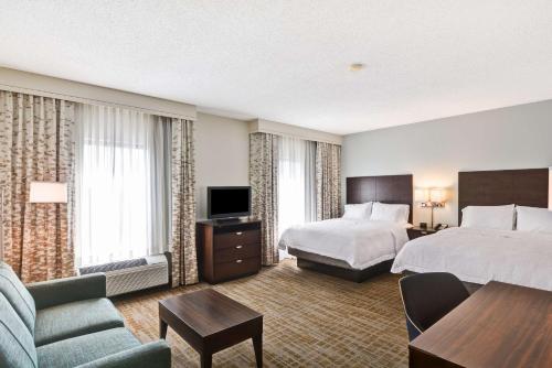 a hotel room with two beds and a television at Hampton Inn & Suites Boynton Beach in Boynton Beach