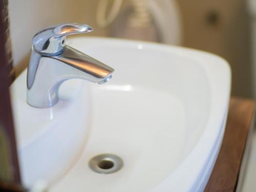 a water faucet on a white toilet in a bathroom at Pousada Suiça Mineira Centro in Monte Verde