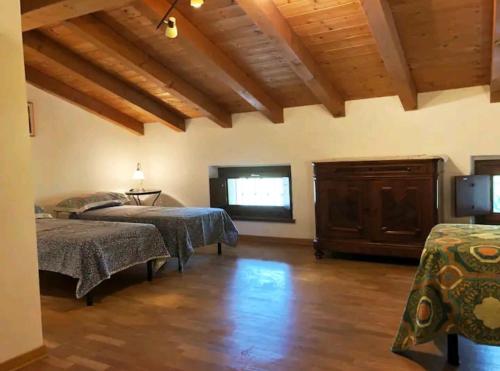 a bedroom with two beds and a window and wooden ceilings at Casa della Meridiana in Clastra
