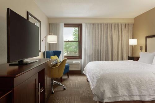 a hotel room with a bed and a flat screen tv at Hampton Inn and Suites Springdale in Springdale