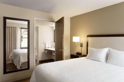 a hotel room with a bed and a mirror at Hampton Inn and Suites Springdale in Springdale