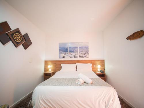 a bedroom with a white bed with a white towel on it at Pousada Suiça Mineira Centro in Monte Verde