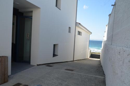 a white building with the ocean in the background at Hostal Náutico de Razo in Carballo