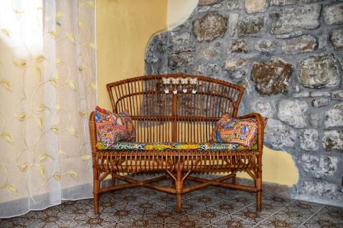a wooden chair sitting in a room with a stone wall at L' Arco Antico in Caccamo