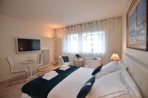 - une chambre avec un grand lit et une télévision dans l'établissement Studio Cannes Gray d'Albion, à Cannes