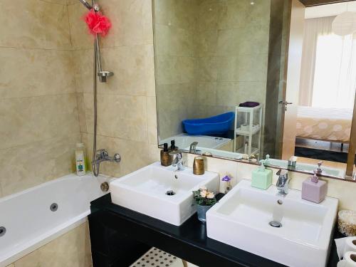 bagno con 2 lavandini, vasca e specchio di Prestigia Golf city Bouskoura Apartment a Bouskoura
