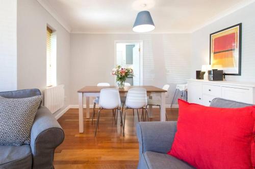uma sala de estar com uma mesa de jantar com uma almofada vermelha em Cosy Modern Oxford Apartment em Oxford
