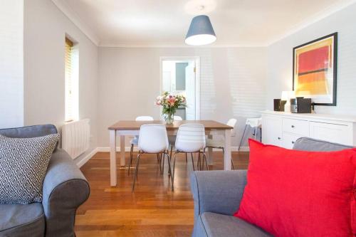 a living room with a dining room table with a red pillow at Cosy Modern Oxford Apartment in Oxford