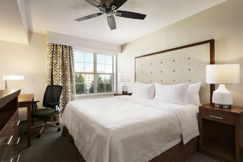 a bedroom with a bed and a desk and a window at Homewood Suites by Hilton Kansas City Airport in Kansas City