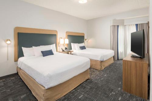 a hotel room with two beds and a flat screen tv at Homewood Suites by Hilton New Orleans in New Orleans