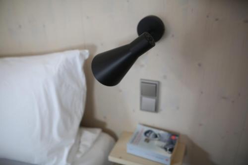 a black lamp on a wall next to a bed at KampenZeit Loft mit traumhaftem Panoramablick in Aschau im Chiemgau