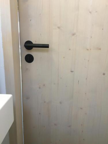 a door with a black handle on a wooden wall at KampenZeit Loft mit traumhaftem Panoramablick in Aschau im Chiemgau