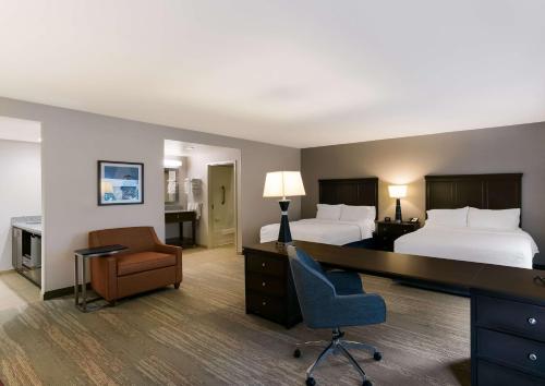 Hampton Inn & Suites Wilmington Christiana في نيوارك: غرفة فندقية بسريرين ومكتب وكرسي