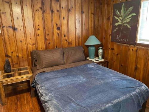 een slaapkamer met een bed, een lamp en houten wanden bij Derby City Getaway in Louisville