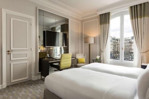 a hotel room with a bed and a desk and a television at Hilton Paris Opera in Paris