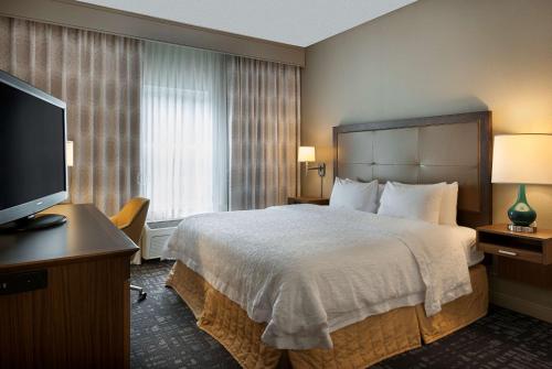 a hotel room with a bed and a flat screen tv at Hampton Inn & Suites Charlotte/Pineville in Charlotte