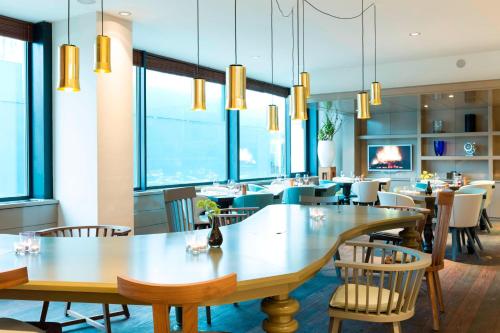 a restaurant with tables and chairs and windows at Marriott Hotel The Hague in The Hague